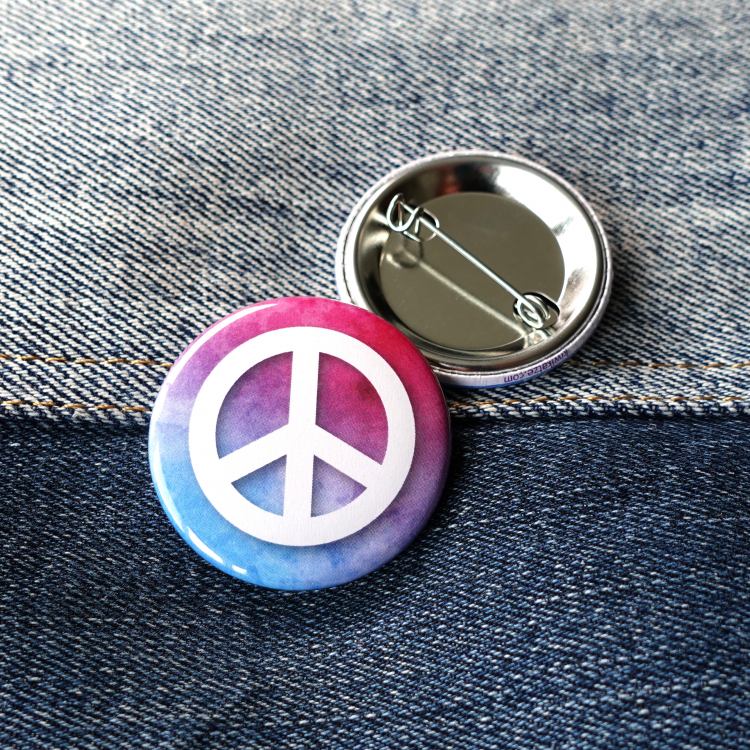 Ansteckbutton Peacezeichen auf Farbwolke auf Jeans mit Rückseite